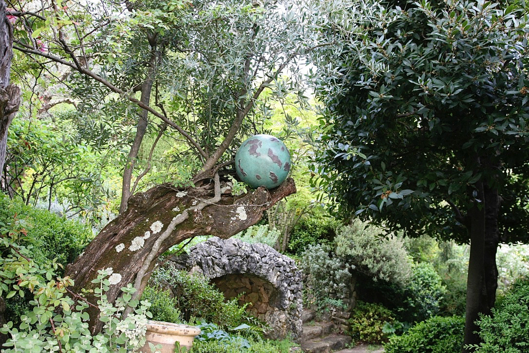 Bronze sphere sculpture in situ on olive tree branch