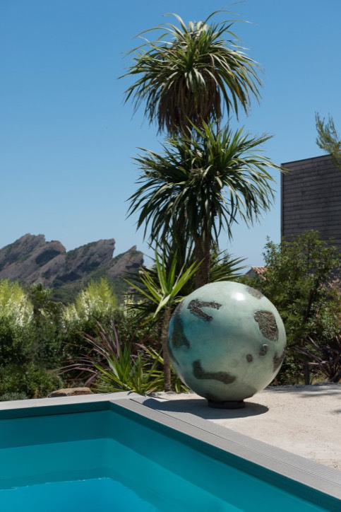 Bronze sphere sculpture in situ by poolside with mountain view